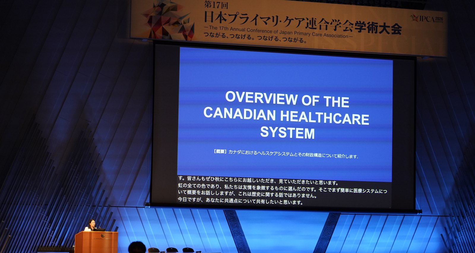 On the main screen, an English slide from the Canadian talk shows live Japanese captions underneath it.