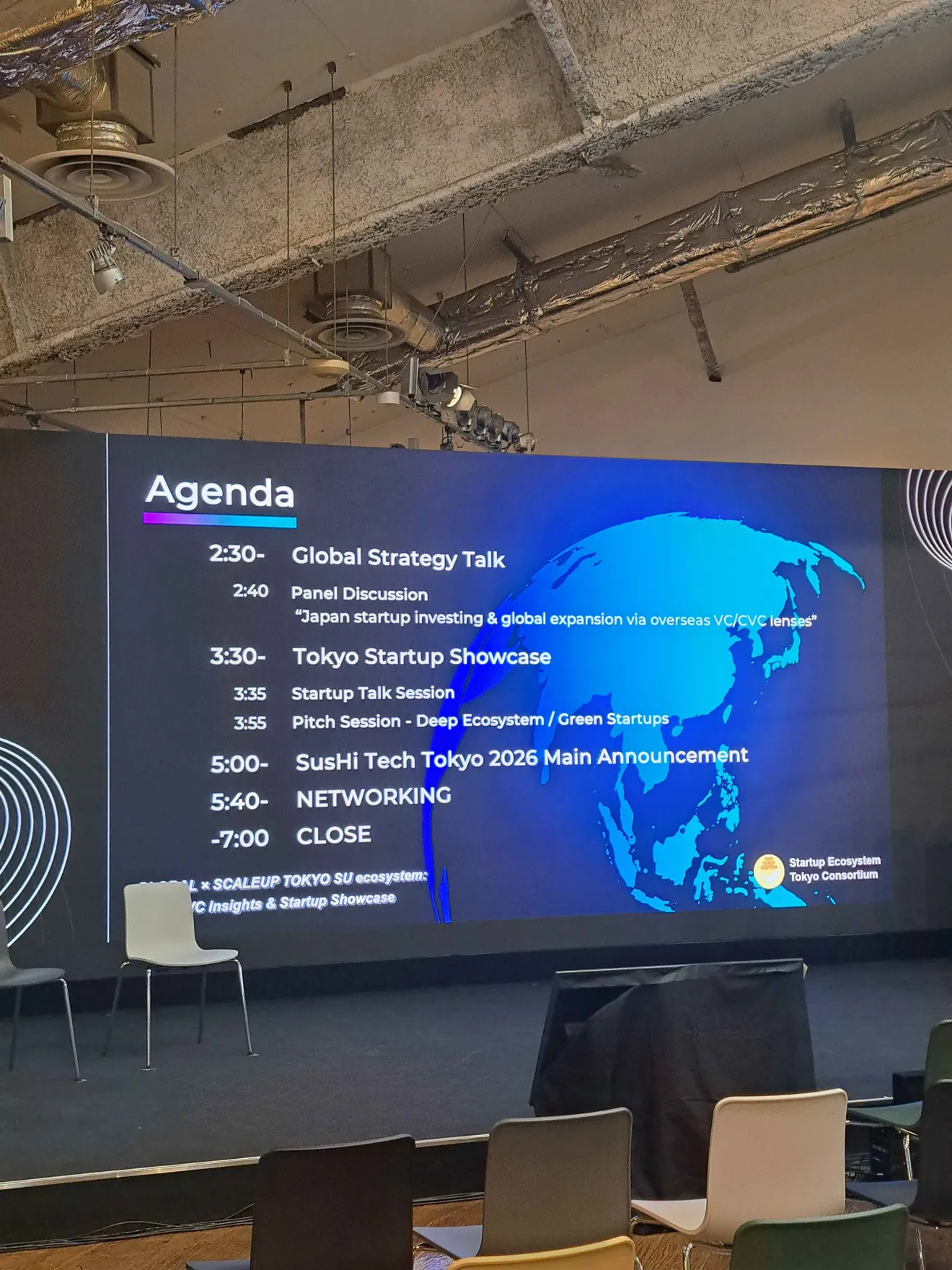 Event agenda displayed on the main stage at Tokyo Innovation Base